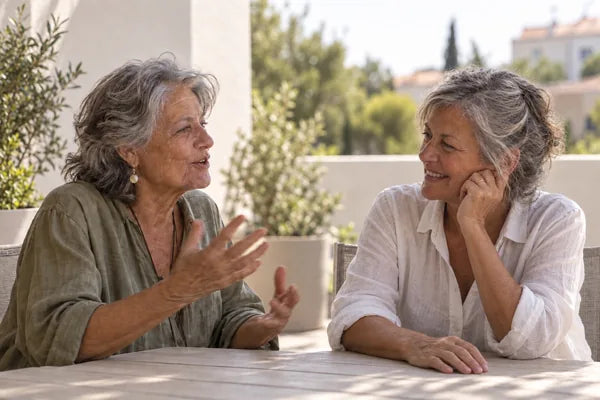 Dos amigas mayores conversan en una terraza soleada